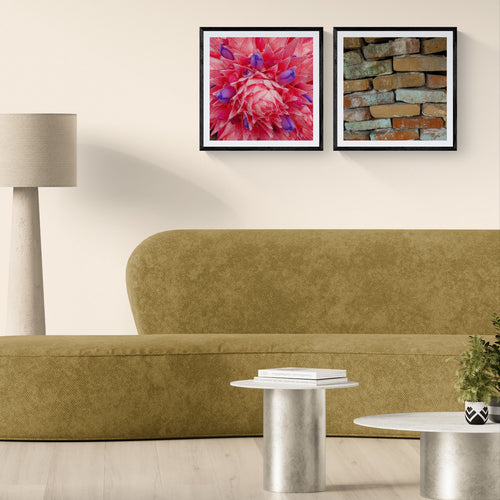 Two 20 × 20 matte photographic art prints, All At Once and Pastel Tense, shown in black square frames above a neutral sofa in a modern living room.