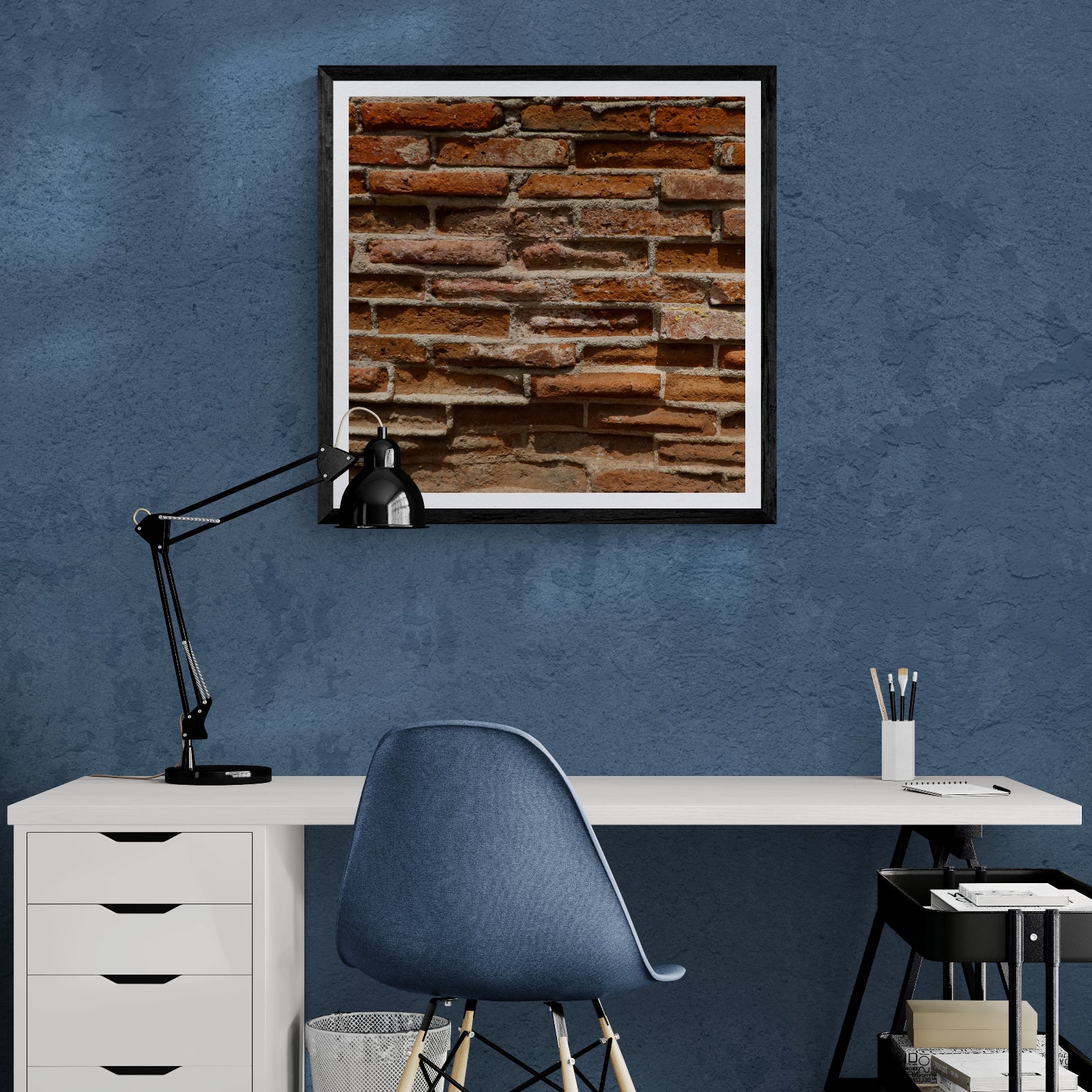 As It Stands weathered brick photography art print displayed as 30 × 30 wall art in a black frame above a desk in a blue home office.