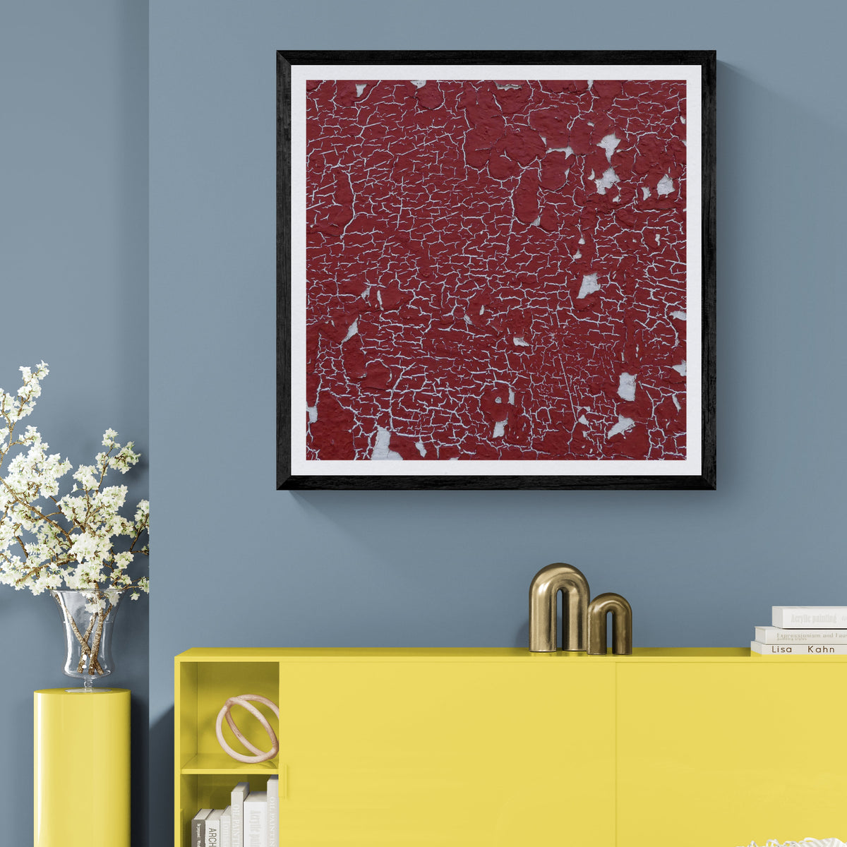 Cracking Up red cracked paint texture art print displayed as 30 × 30 wall art in a black frame above a yellow cabinet in a colorful living room.