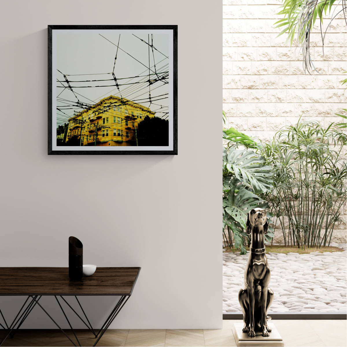Electric Veins urban film photograph of a yellow building beneath a dense network of overhead wires displayed as 30 × 30 wall art in a black frame in a modern neutral interior.