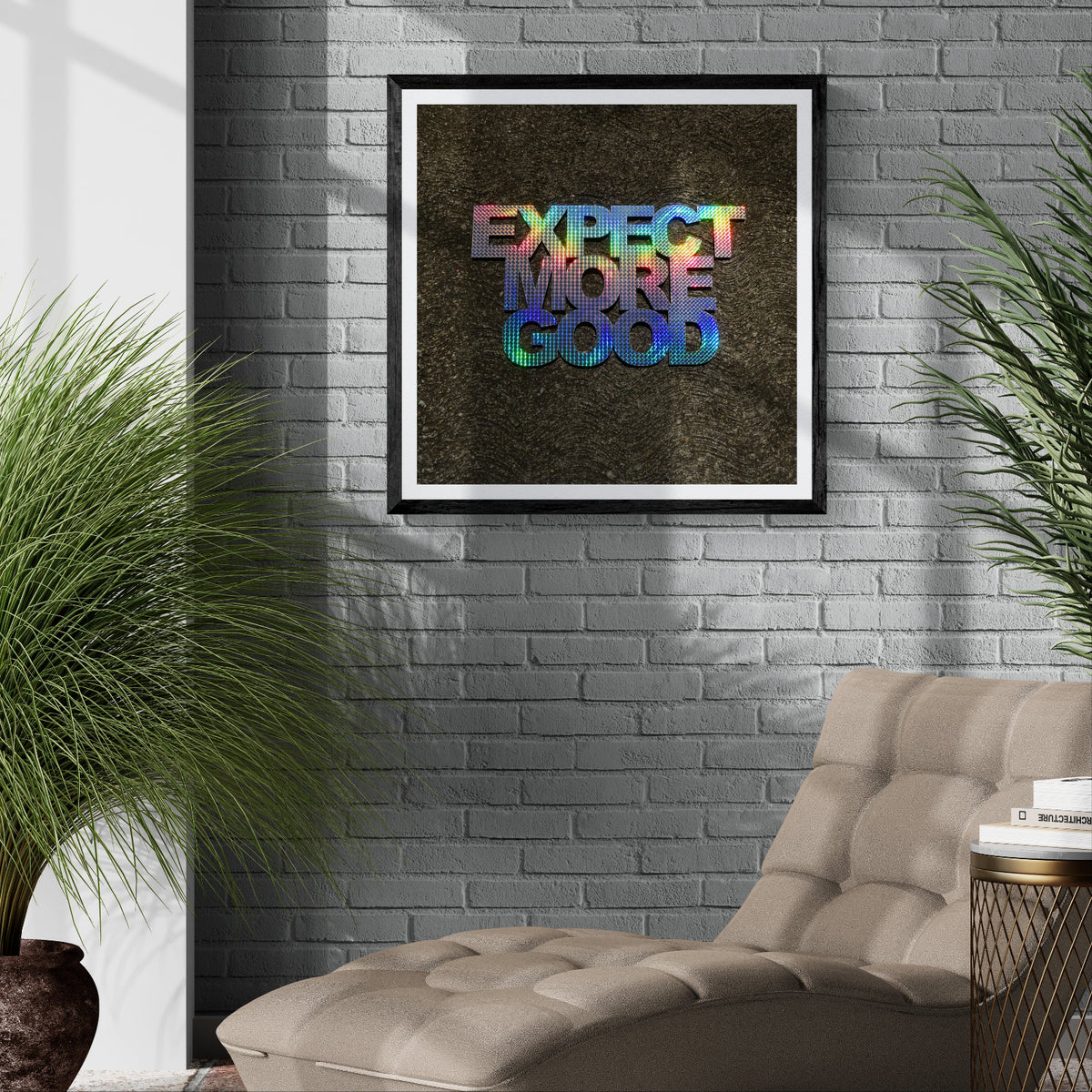 Expect More Good holographic typography art print displayed as 30 × 30 wall art in a black frame on a gray brick wall in a modern living room.