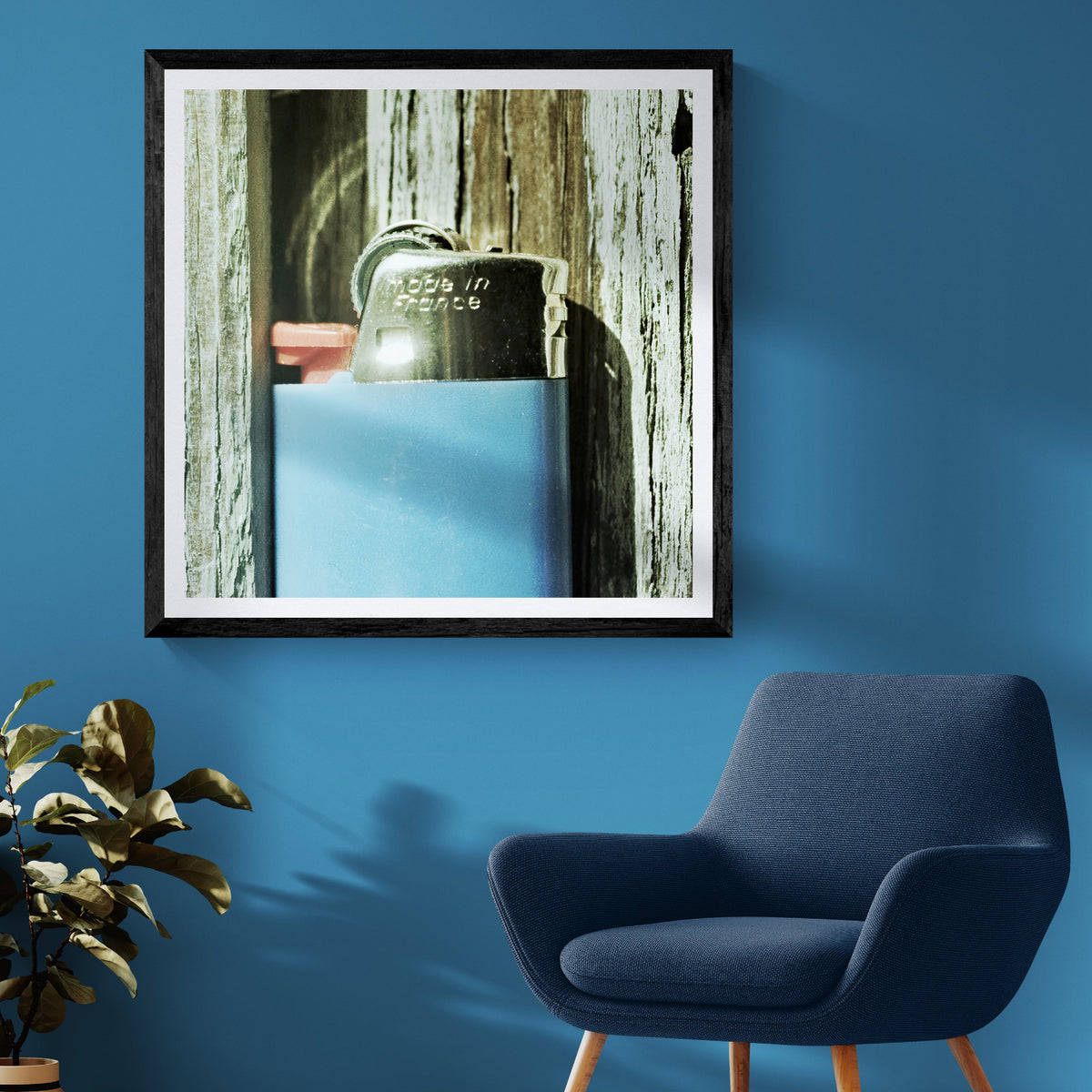 French Spark vintage lighter film photography art print displayed as 30 × 30 wall art in a black frame above a blue chair in a sunlit living room.