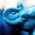 Glazed Memory blue-toned film photograph featuring a close-up of a ceramic animal figure with soft focus, deep shadows and luminous highlights.