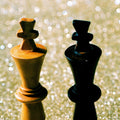 King Things film photograph of two chess kings reflected on a glittering surface, one illuminated in warm gold and the other falling into deep shadow.